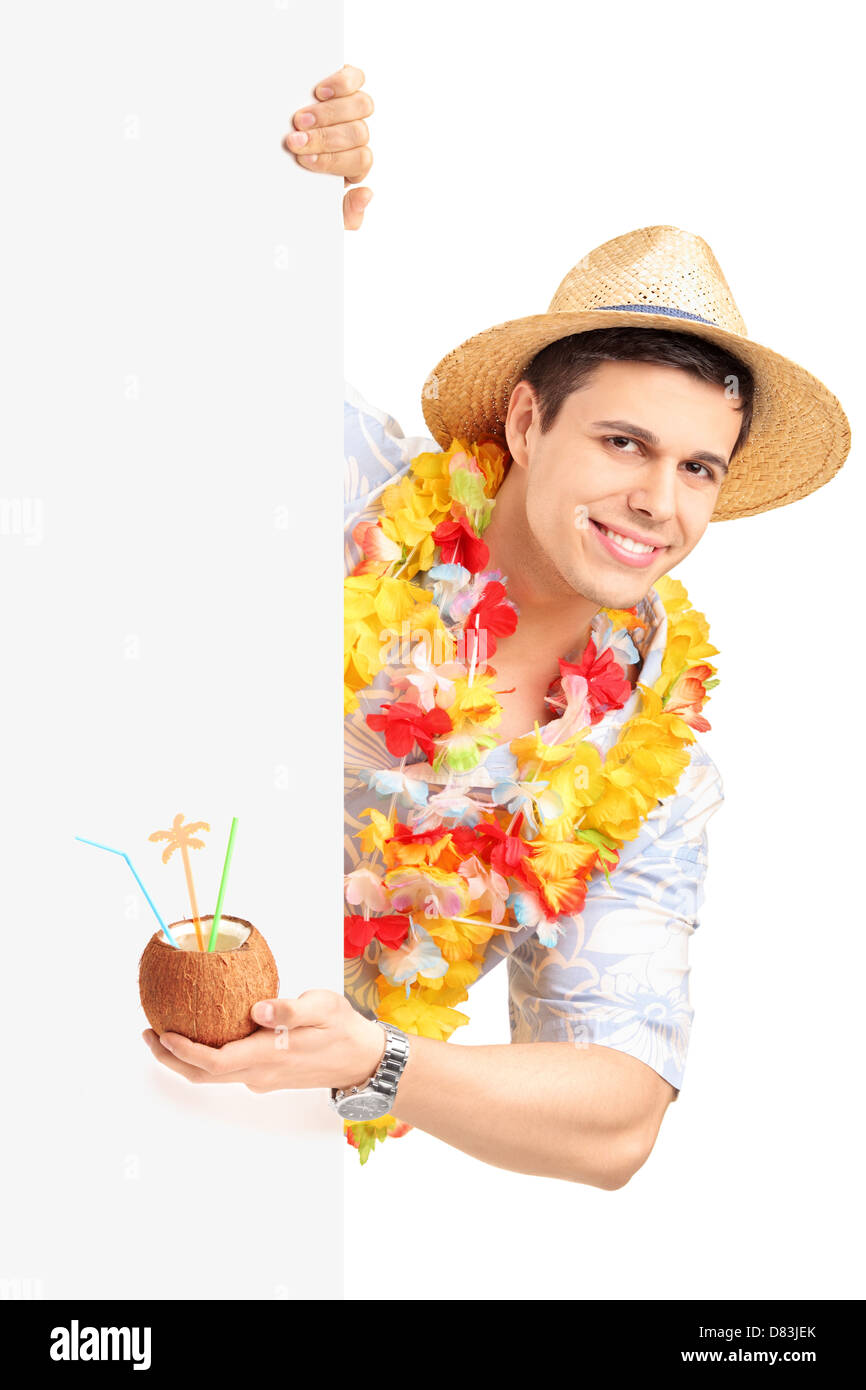 Lächelnder Mann in traditioneller Tracht hinter eine Blindplatte hält eine Kokosnuss cocktail isoliert auf weißem Hintergrund Stockfoto