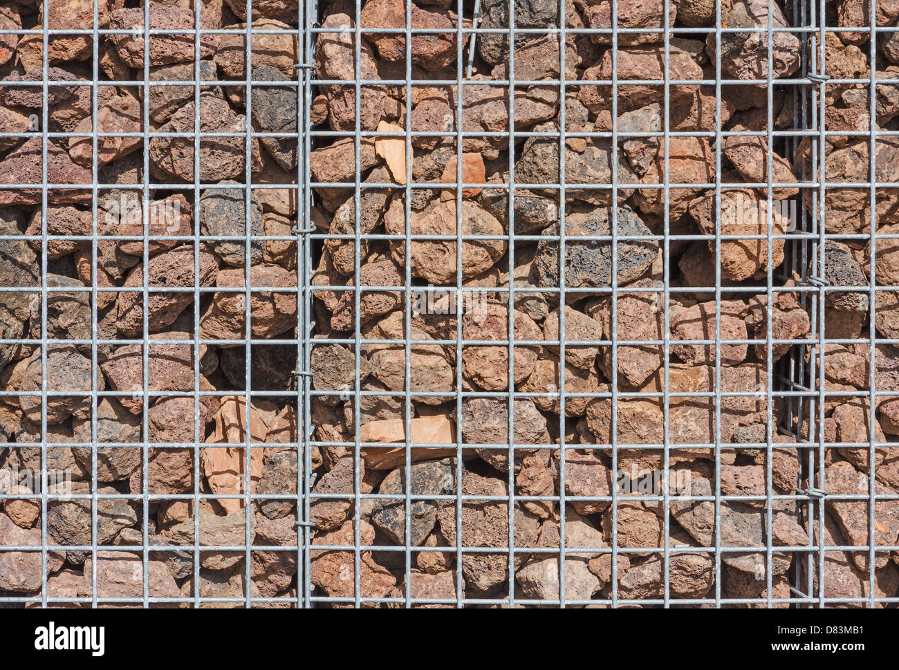 Gabion Wand gefüllt mit Lavasteinen in der Sonne Stockfoto