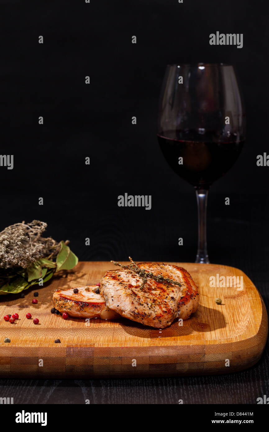 Gegrilltes Steak mit Glas Rotwein auf dunklem Hintergrund Stockfoto
