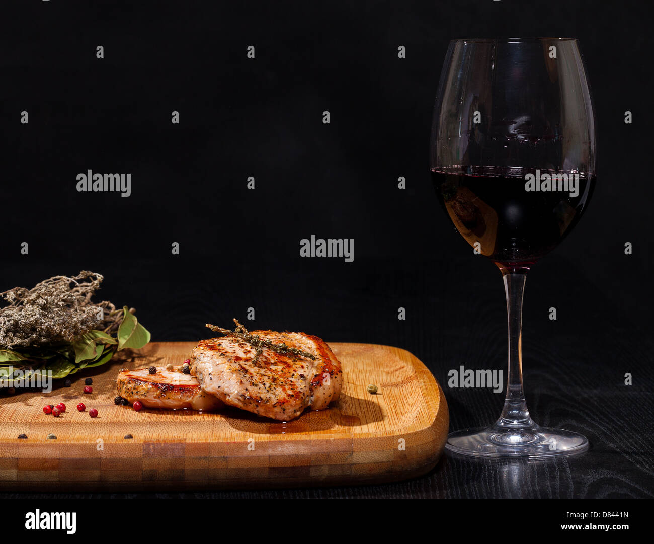 Gegrilltes Steak mit Glas Rotwein auf dunklem Hintergrund Stockfoto