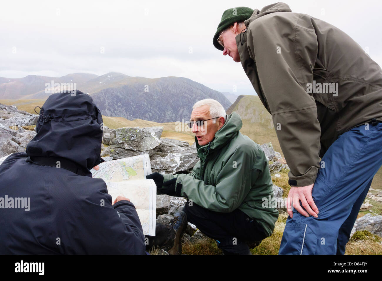 Drei männliche ältere Wanderer Senioren Lesen eines Ordnance Survey map auf einen Spaziergang bis Elidir Fawr in Berge von Snowdonia, North Wales, UK, Großbritannien Stockfoto