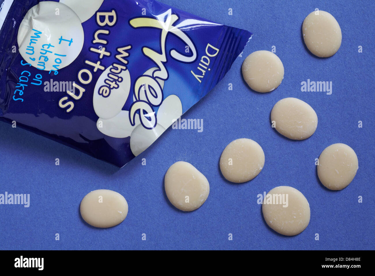 Paket der Molkerei freie weiße Tasten Pralinen mit verschüttetem Inhalt auf blauem Hintergrund verschüttet Stockfoto