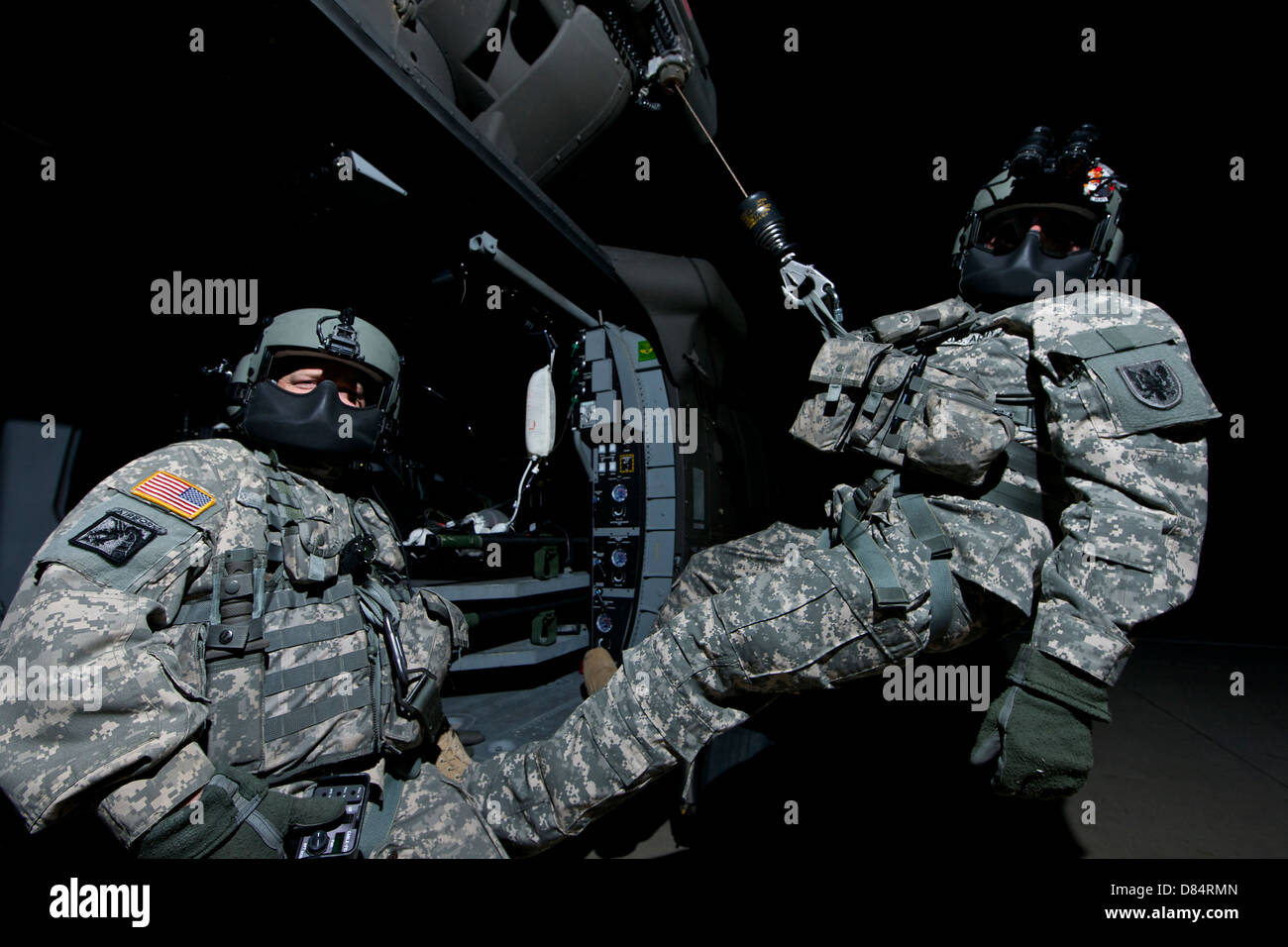 Truppführer sitzt in der Tür ein UH-60 Black Hawk Medevac-Hubschrauber während der Medic auf der Hebebühne steht sitzt. Stockfoto