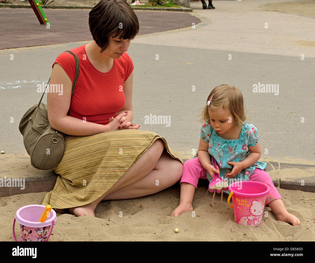 2 Jahre altes Mädchen mit Mutter im Sandkasten spielen Spielzeug Spielplatz Stockfoto