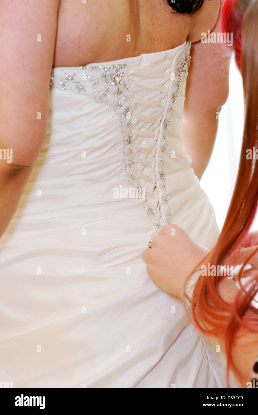 Braut, die immer ihr Kleid von hinten hergerichtet Stockfoto