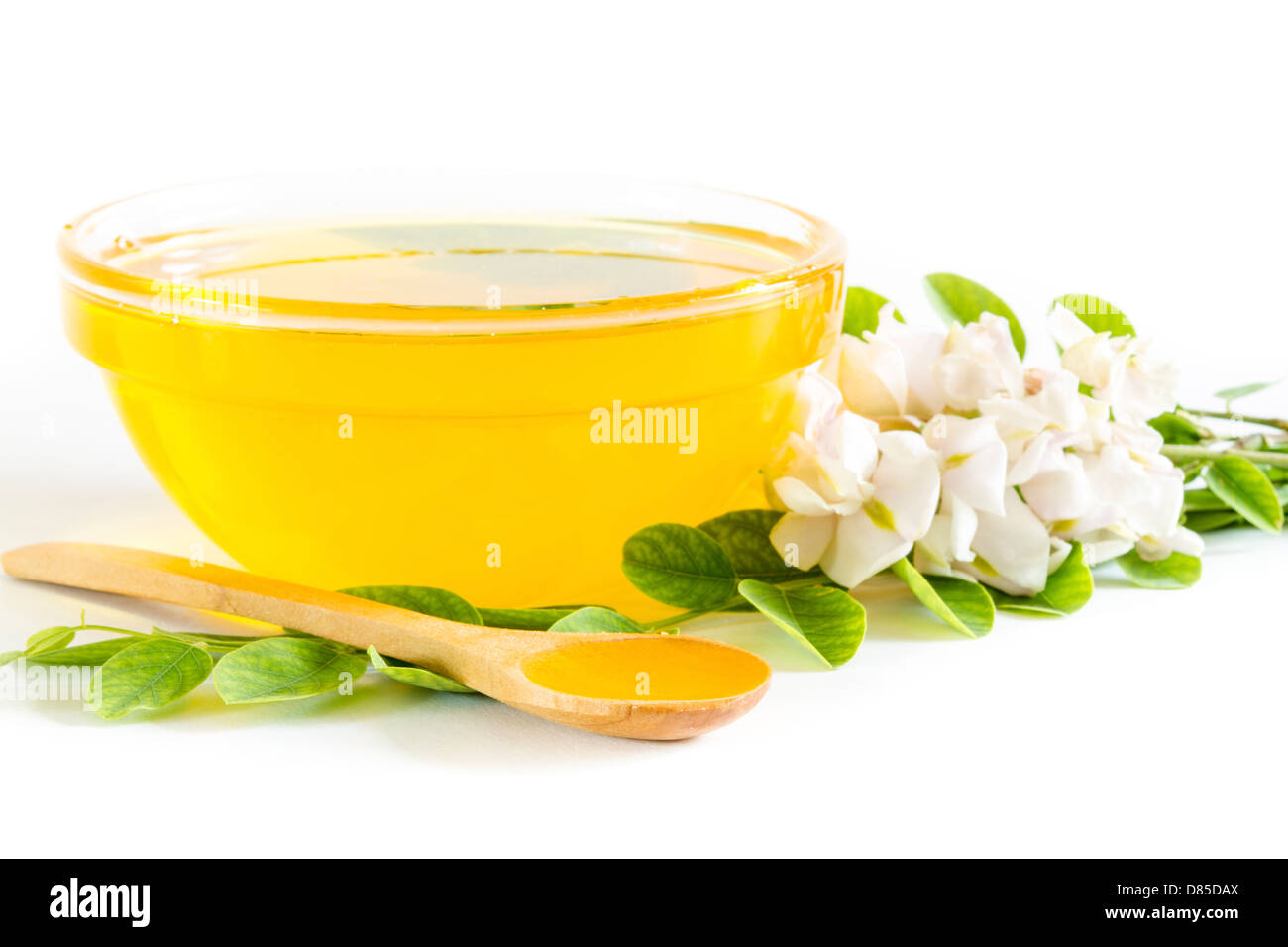 Honig in Glasschale und Akazien auf weißem Hintergrund Stockfoto