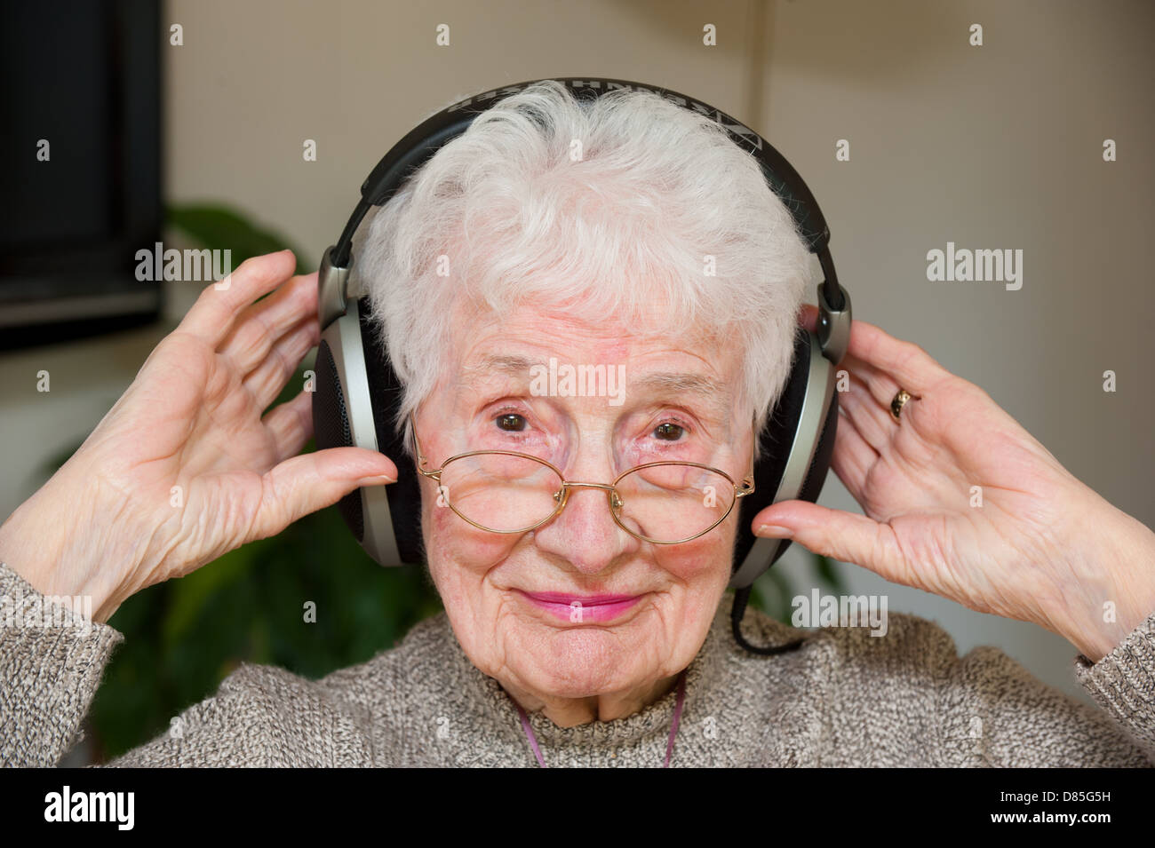 Eine ältere Frau, die äußere Ohr Kopfhörer tragen Stockfoto