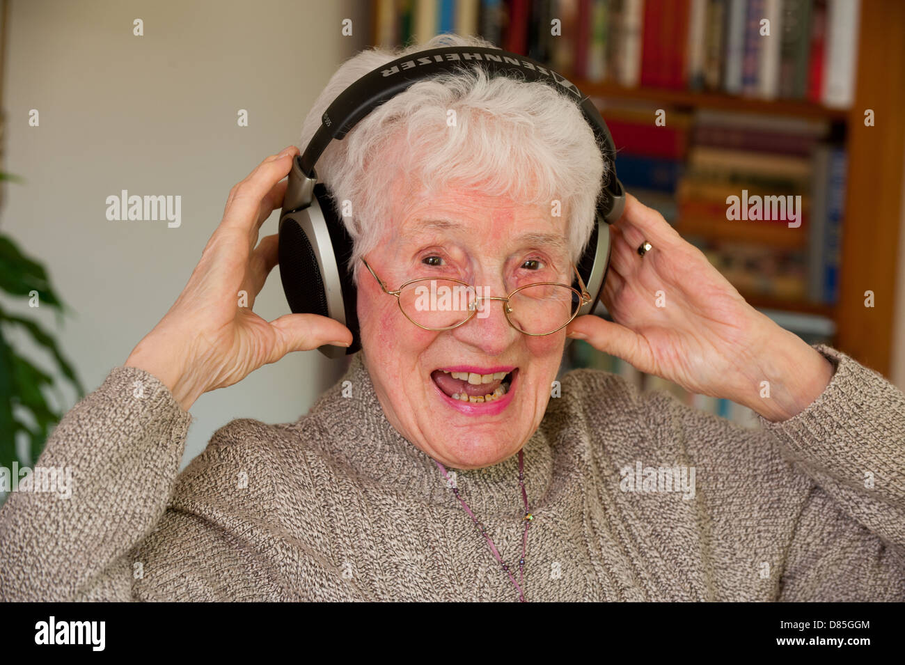Eine ältere Frau, die äußere Ohr Kopfhörer tragen Stockfoto