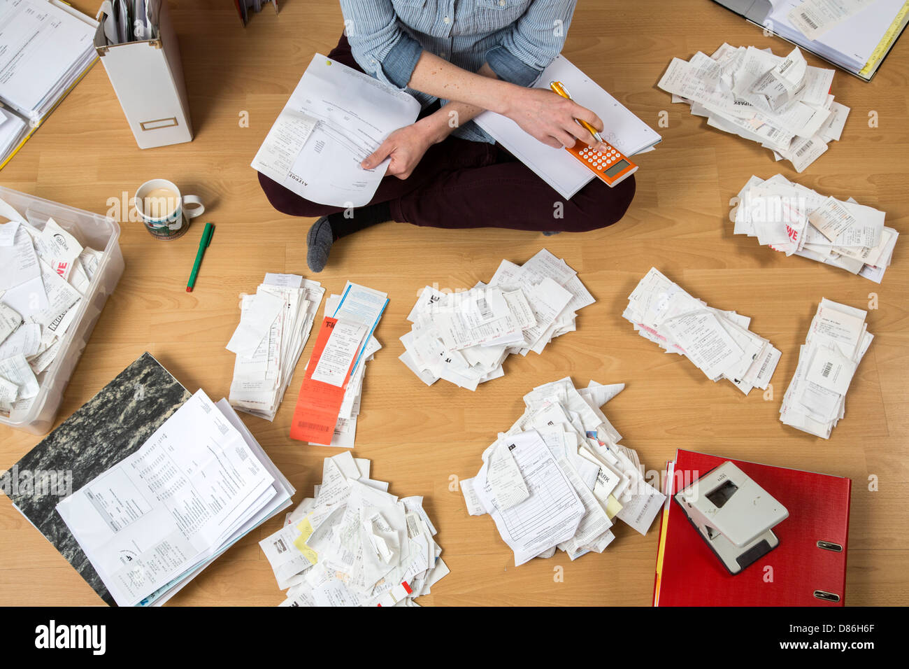 Junge Frau sitzt zu Hause und Rechnungen, Quittungen und andere Papiere für ihre Steuererklärung zu klären. Stockfoto