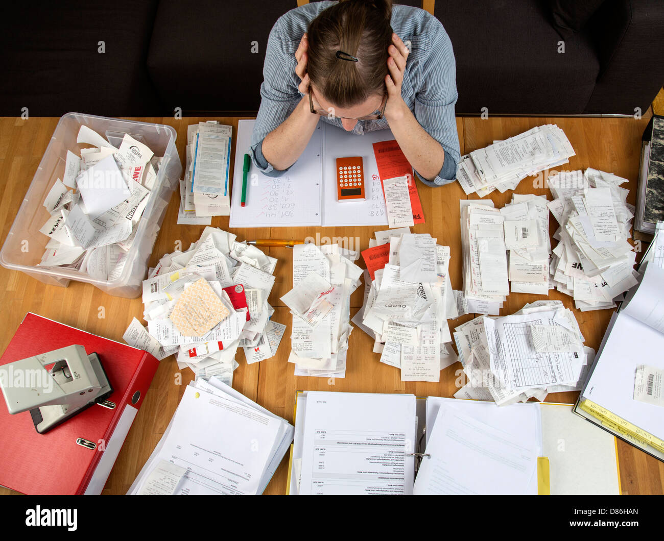 Junge Frau sitzt zu Hause und Rechnungen, Quittungen und andere Papiere für ihre Steuererklärung zu klären. Stockfoto