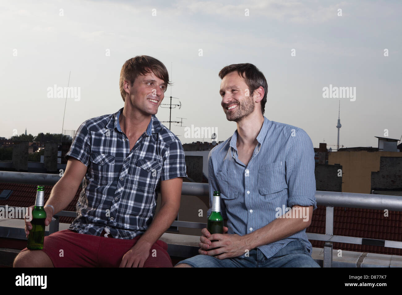 Deutschland, Berlin, Männer mit Flaschen auf Dachterrasse, Lächeln Stockfoto