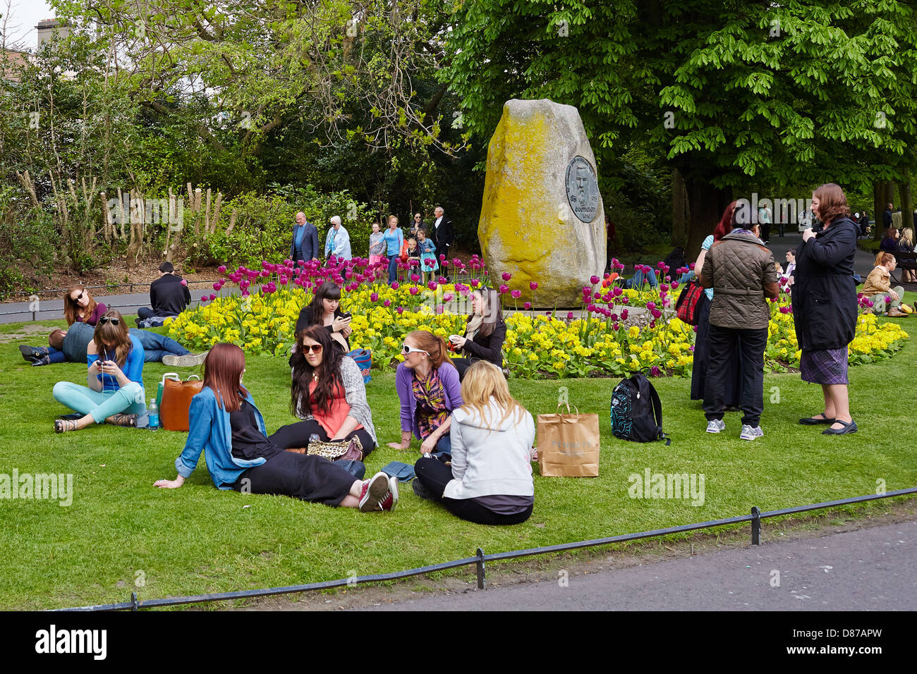 Junge Leute sitzen und entspannen Sie an einem sonnigen Tag in St. Stephens Green Park, Dublin, Republik Irland Stockfoto