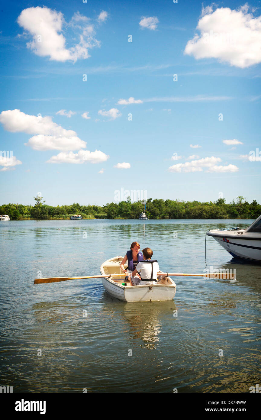 Zwei junge Menschen nehmen ein Ruderboot auf den Norfolk Broads in einem heißen Sommertag Stockfoto