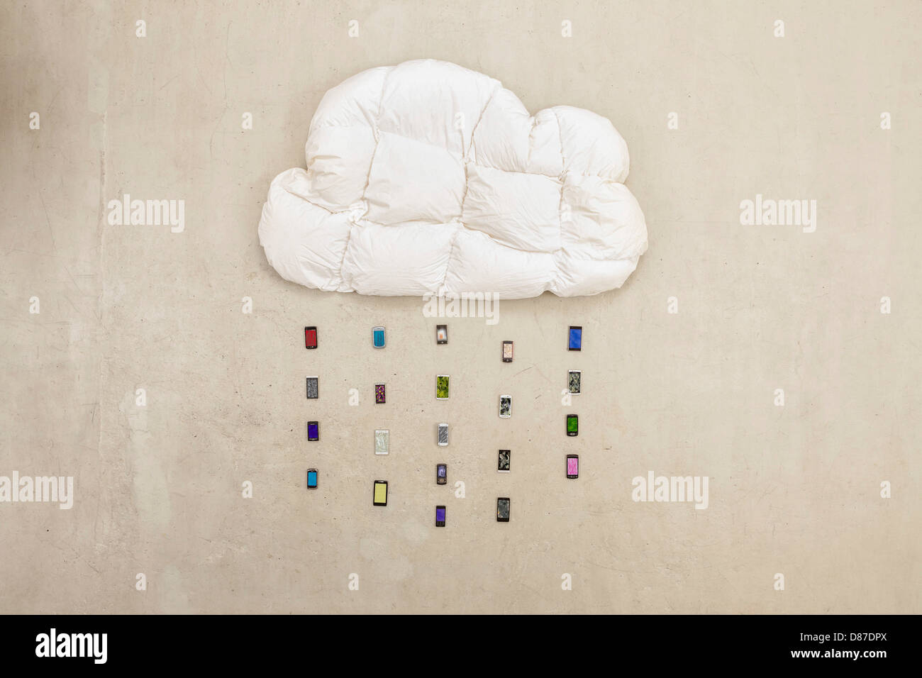 Cloud-Form-Kissen mit Handys bilden Regen auf Beige Hintergrund Stockfoto