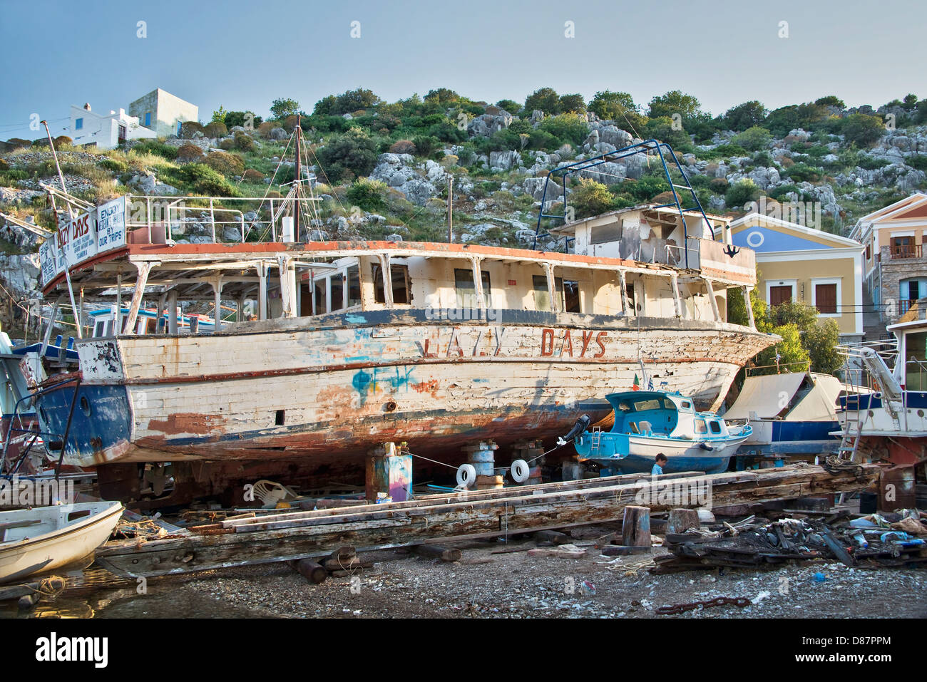 Kind spielt in der Nähe ein altes Schiff in der kleinen Werft von Symi - Dodekanes-Inseln, Griechenland Stockfoto