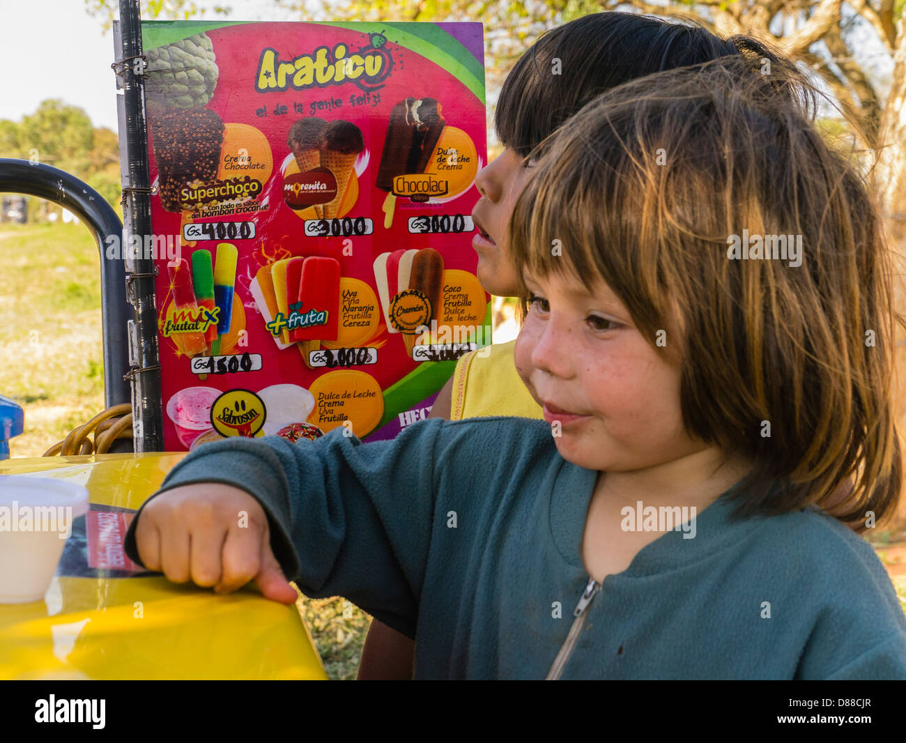 Zwei hispanischen Mädchen stehen das Zeichen Werbung die Leckereien Eiswagen an ab. Stockfoto
