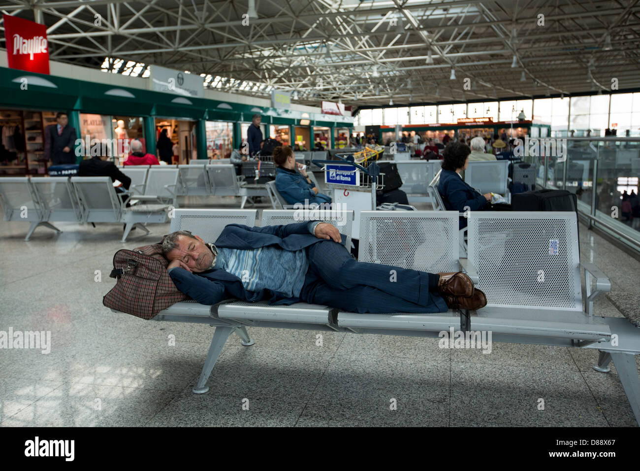 ein Mann schläft in der Abflughalle am Flughafen. Stockfoto