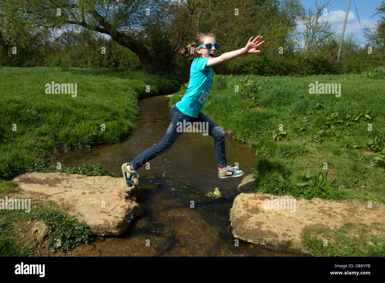 junge Mädchen, die über einen Bach springen Stockfoto