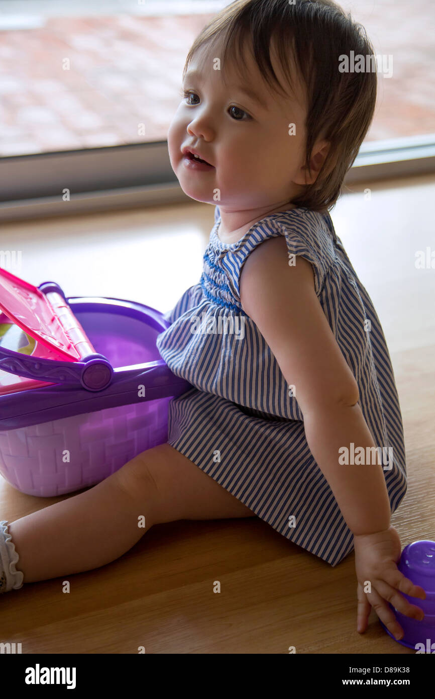 14 Monate altes Babymädchen spielen mit Korb Stockfoto