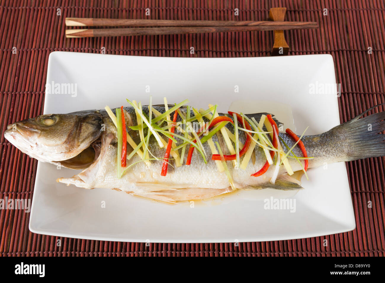 Gedünsteter Fisch - chinesischen Stil gedünstet Seebarsch mit Ingwer, Chili und Frühlingszwiebeln garniert. Stockfoto