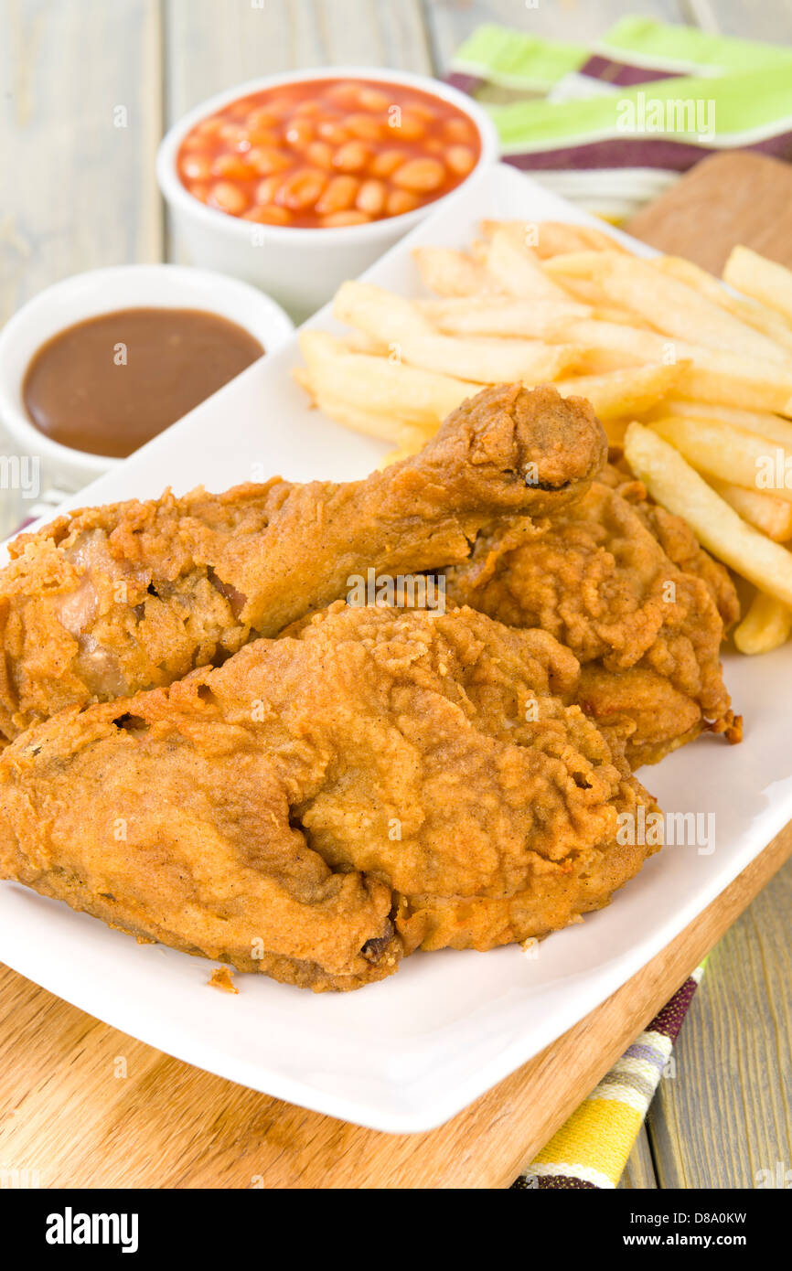 Fried Chicken & Chips - Hähnchenteile auf den Knochen in würziger Mehl überzogen und frittiert. Pommes frites, Bohnen und Soße Seiten. Stockfoto