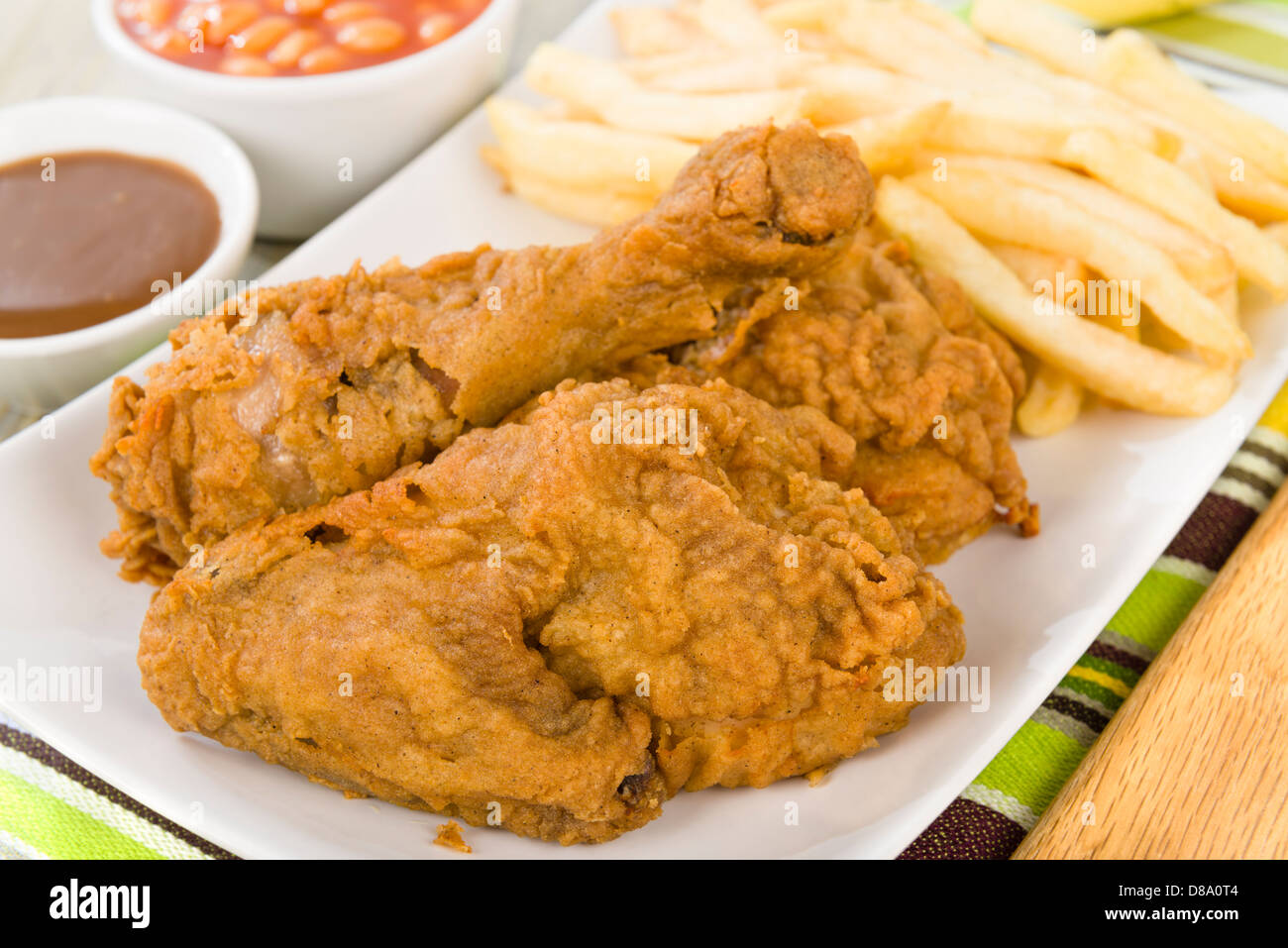 Fried Chicken & Chips - Hähnchenteile auf den Knochen in würziger Mehl überzogen und frittiert. Pommes frites, Bohnen und Soße Seiten. Stockfoto