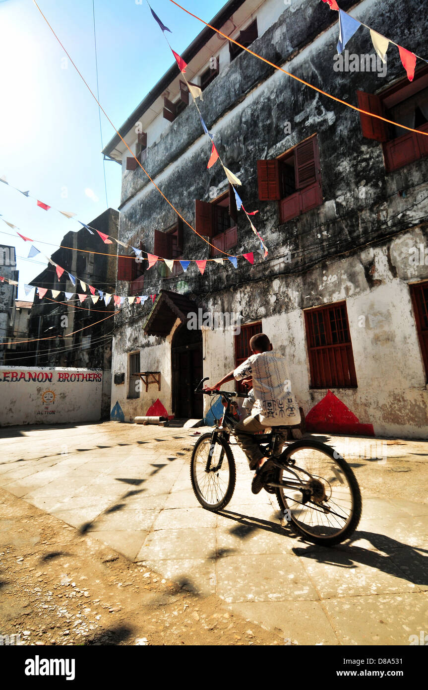 Ein junger Boy sein Fahrrad in den alten Straßen von Stonecity unter den roten, blauen und weißen Fahnen Stockfoto
