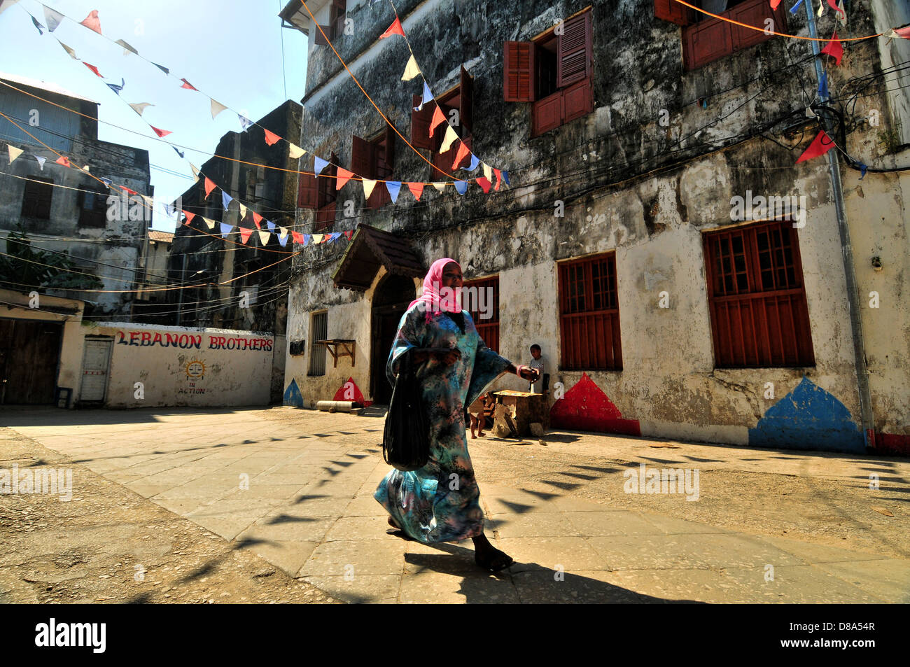 Muslimische jungen Frau zu Fuß in die Fahnen geschmückt Straßen von Stonecity, Zanzibar Stockfoto