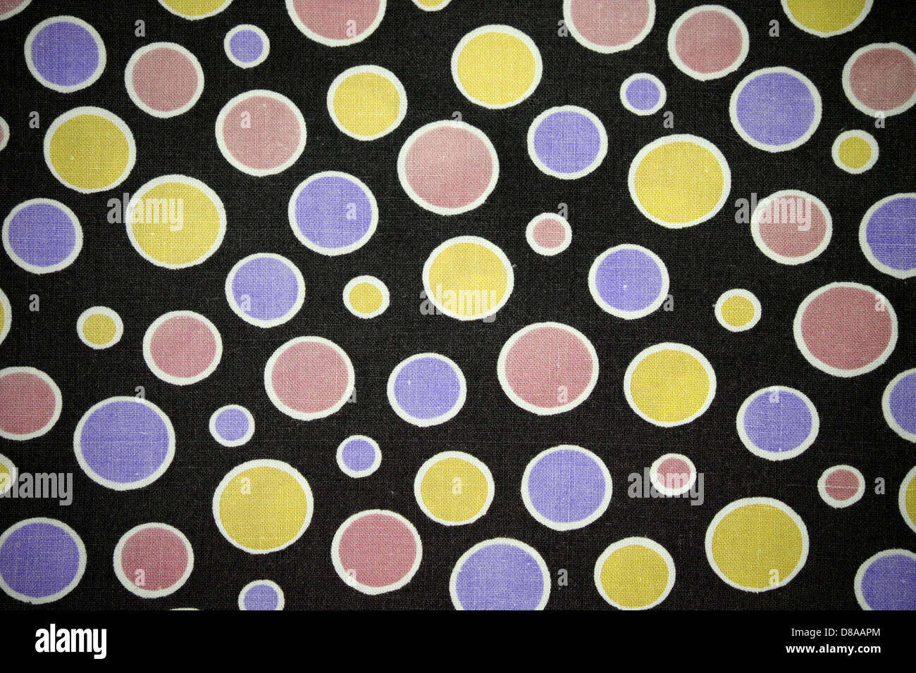 Ein Nahaufnahme-Bild aus schwarzem Stoff mit rosa, lila und gelben Punkten, die ein verspieltes und lebendiges Muster zeigen. Die Stoffstruktur verleiht dem Design Tiefe und visuelles Interesse. Stockfoto