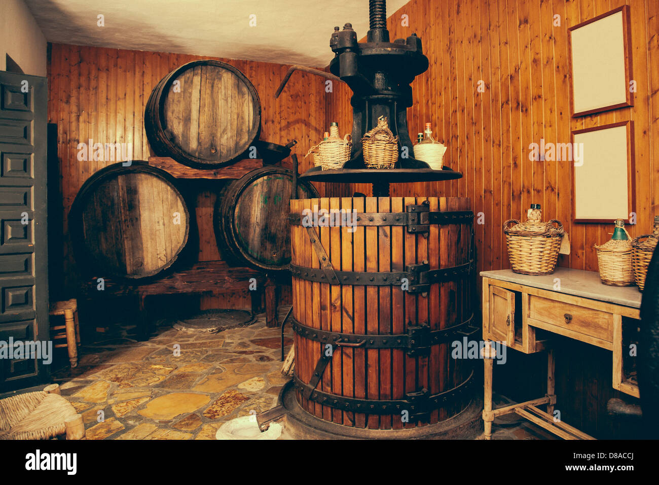 Weinpresse und Fässer im spanischen Keller Stockfoto