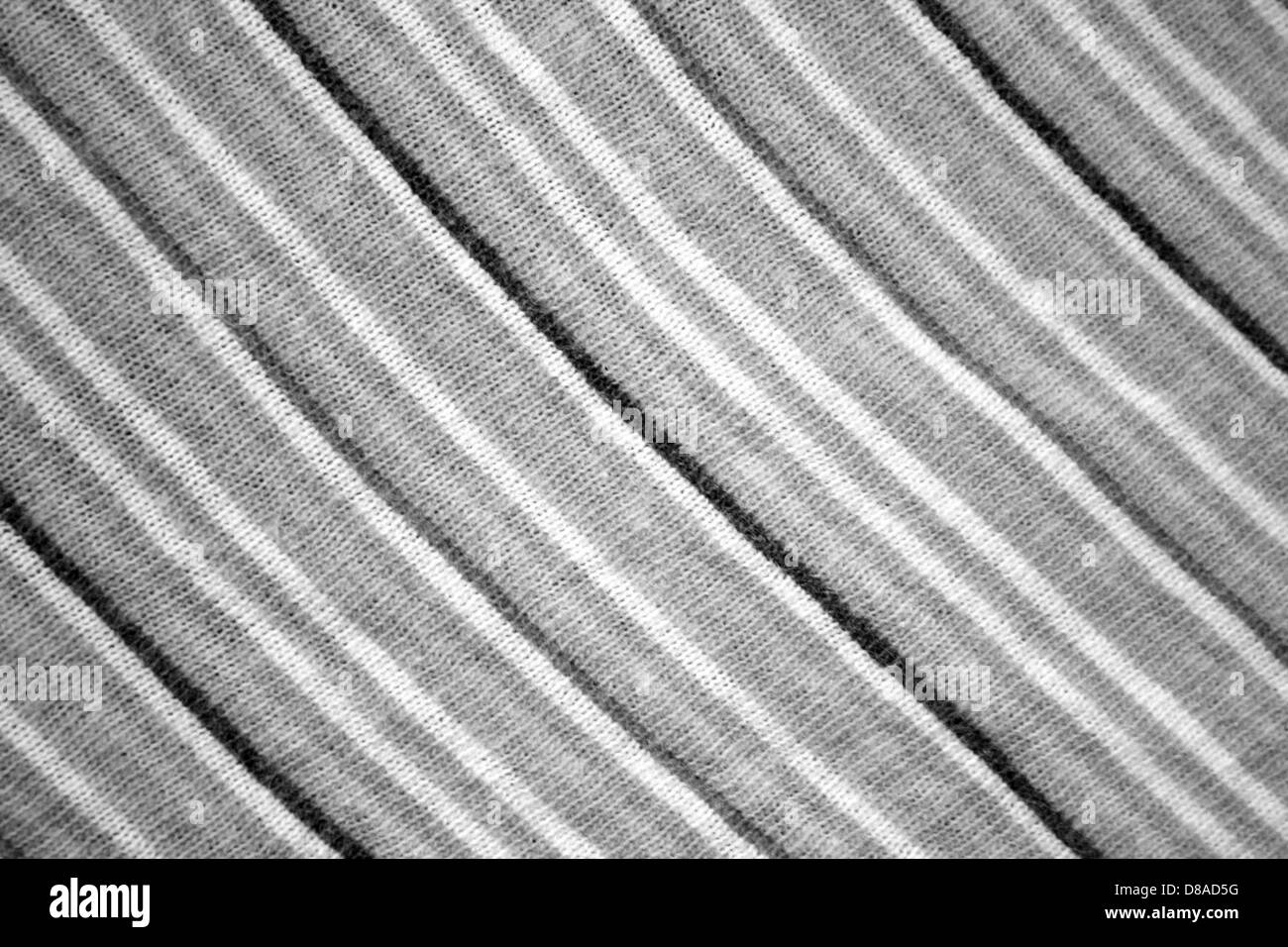 Eine Nahaufnahme aus diagonal gestreiftem Strickmaterial mit einer Mischung aus Grau, Schwarz und weiß. Diese Textur verleiht Textilien, die in Mode oder Wohnkultur verwendet werden, Tiefe und visuelles Interesse. Stockfoto