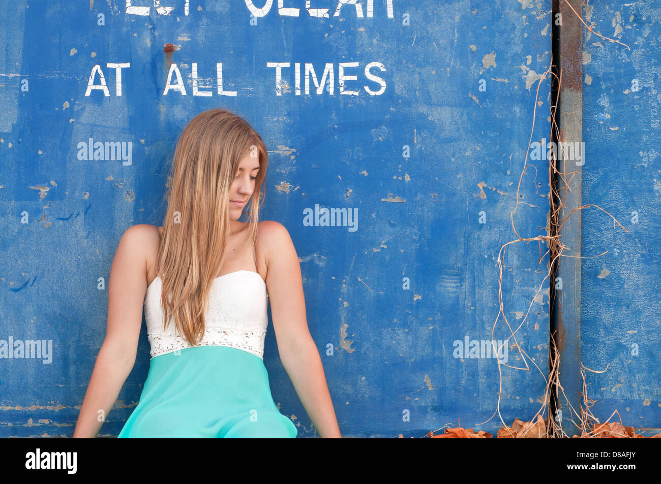 Junge Frau auf der Suche von Kamera, eine alte blaue Tür gelehnt Stockfoto