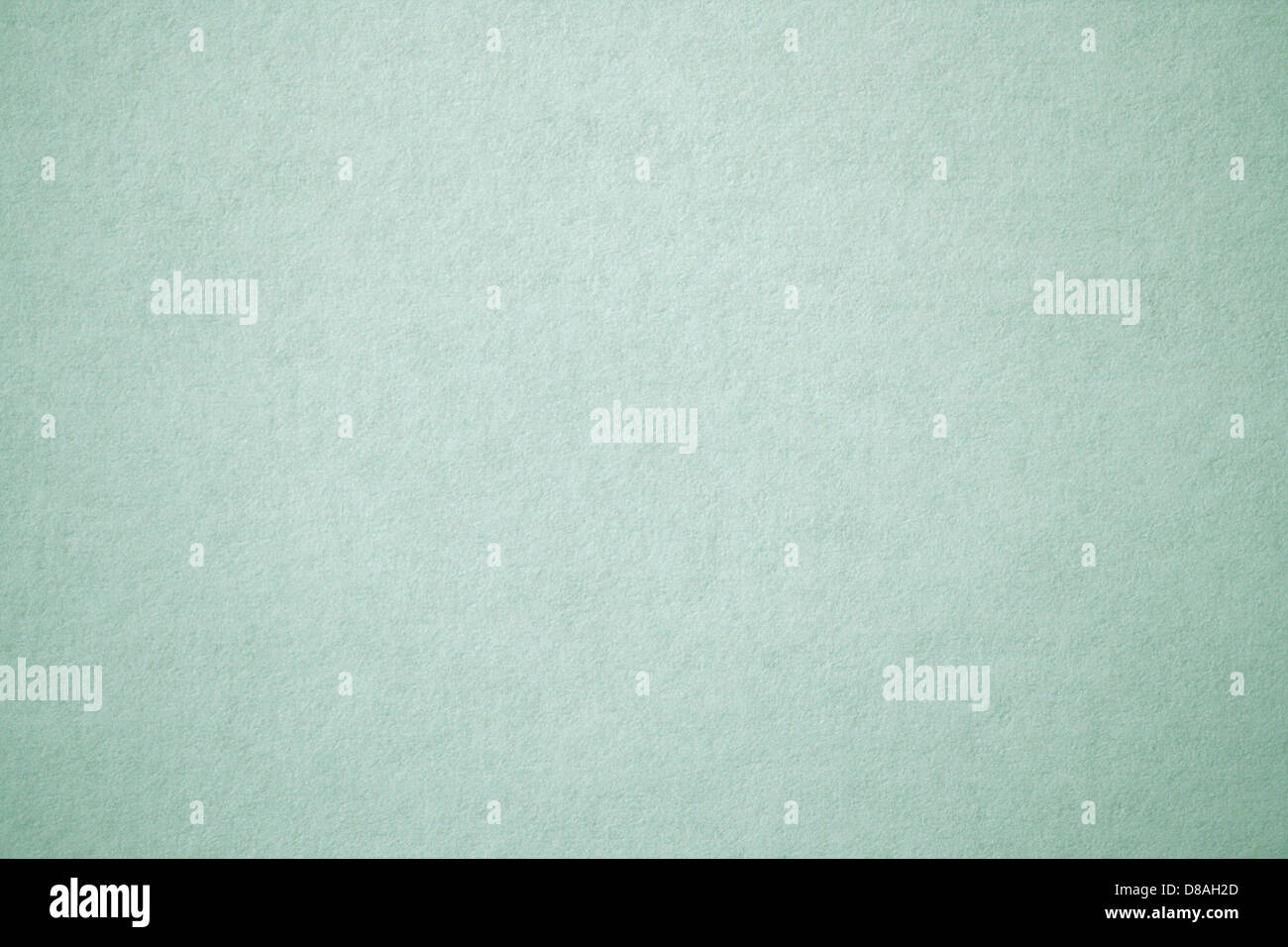 Eine Nahaufnahme aus salbeigrünem, strukturiertem Papier mit einer weichen und beruhigenden Farbe, die eine glatte, aber leicht unebene Oberfläche erzeugt. Ideal für Designprojekte und Hintergründe. Stockfoto