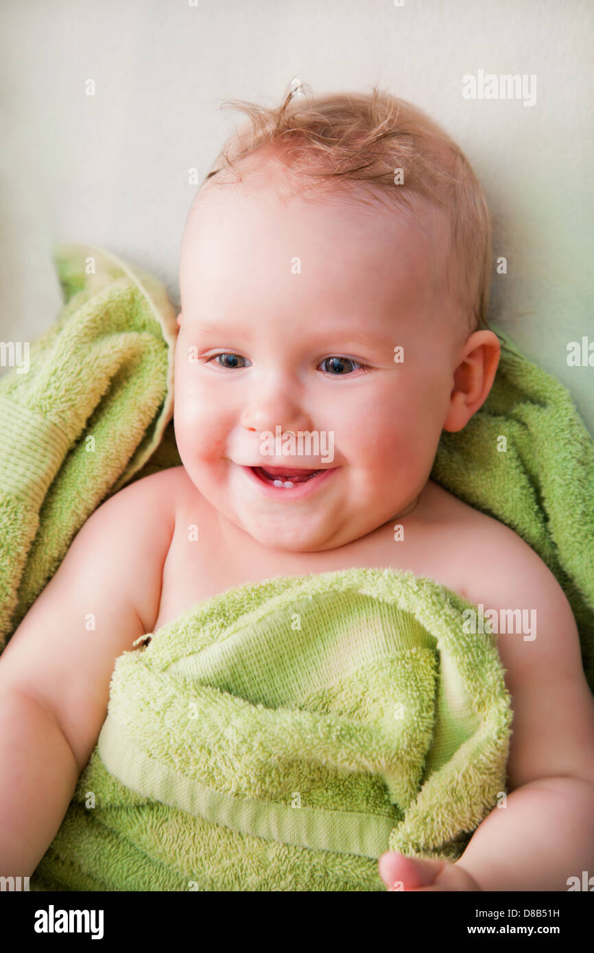 Ein glückliches Lächeln auf den Lippen Baby grünen Handtuch auf Bett liegend Stockfoto