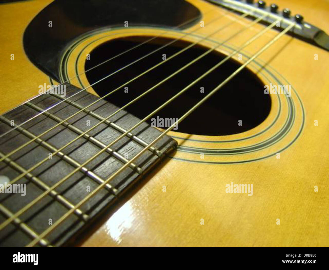 Eine Nahaufnahme einer Akustikgitarre, die sich auf das Klangloch konzentriert. Die glatte, abgerundete Kante des Lochs lässt den Klang klingen, während die natürliche Körnung und Oberfläche des Holzes die Schönheit und Funktion des Instruments unterstreicht. Stockfoto