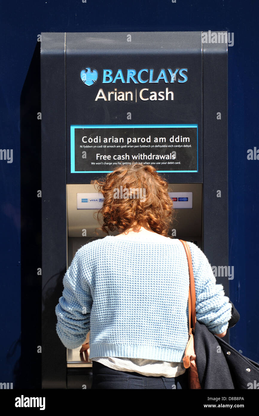 Eine Frau zieht sich Bargeld aus einem Barclays-Geldautomaten / atm. Stockfoto