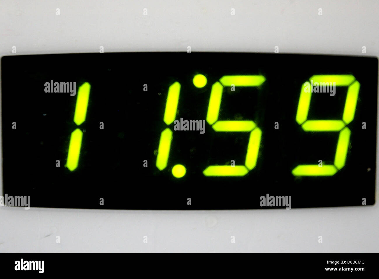 Eine digitale Uhr zeigt die Zeit 11:59, kurz vor Mitternacht, an. Die klare Digitalanzeige der Uhr betont den genauen Moment und erfasst die Erwartung der Zeit, die sich um Mitternacht nähert. Stockfoto