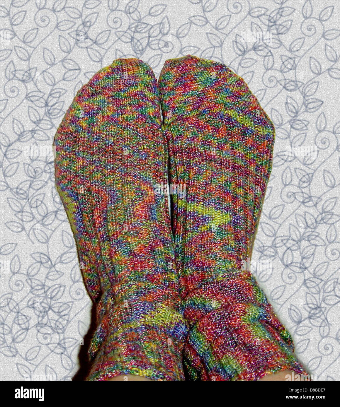Die Füße sind mit farbenfrohen, gemusterten Socken zu sehen. Die Socken verleihen der Szene einen verspielten und lebendigen Touch und heben sowohl Komfort als auch Stil im Alltag hervor. Stockfoto