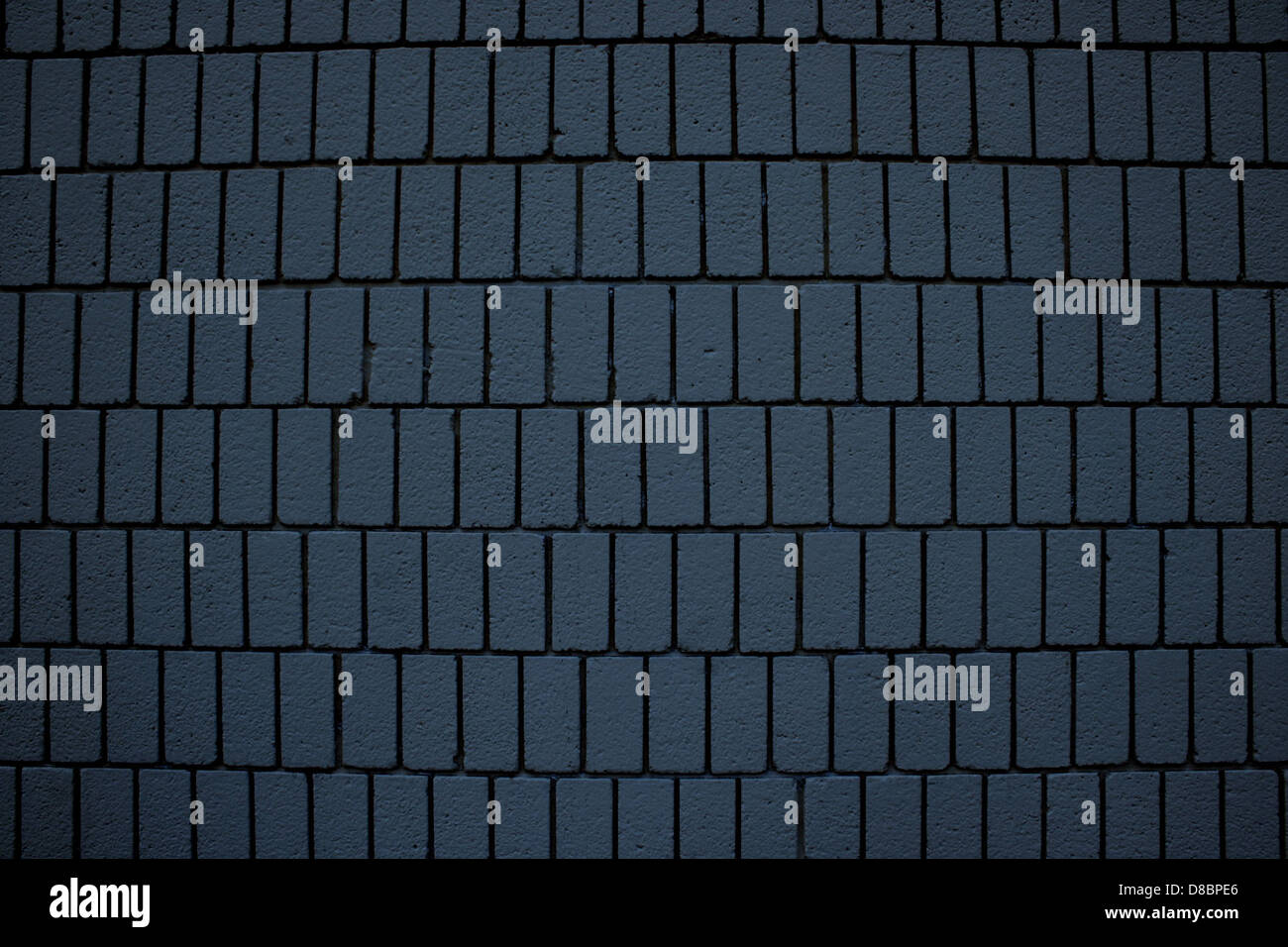 Dieses Bild zeigt eine stahlblaue Ziegelwand mit vertikaler Ziegelplatzierung. Die kühlen Blautöne verleihen der Wand ein modernes, industrielles Flair, während die vertikale Ausrichtung der Ziegelsteine ein Element von visuellem Interesse hinzufügt. Solche Wände werden häufig in zeitgenössischer Architektur verwendet und bieten eine stilvolle und langlebige Oberfläche für Innen- und Außendesign. Stockfoto