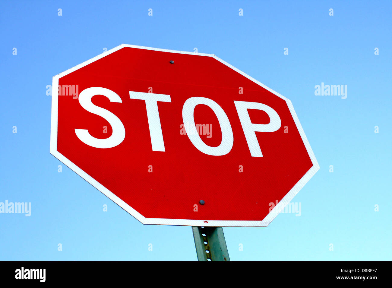 Ein rotes Stoppschild steht deutlich vor einem klaren blauen Himmel. Der Kontrast zwischen dem leuchtenden Rot des Schildes und dem tiefblauen Himmel unterstreicht die Klarheit des Verkehrszeichens und seine Bedeutung für die Straßenverkehrssicherheit. Stockfoto