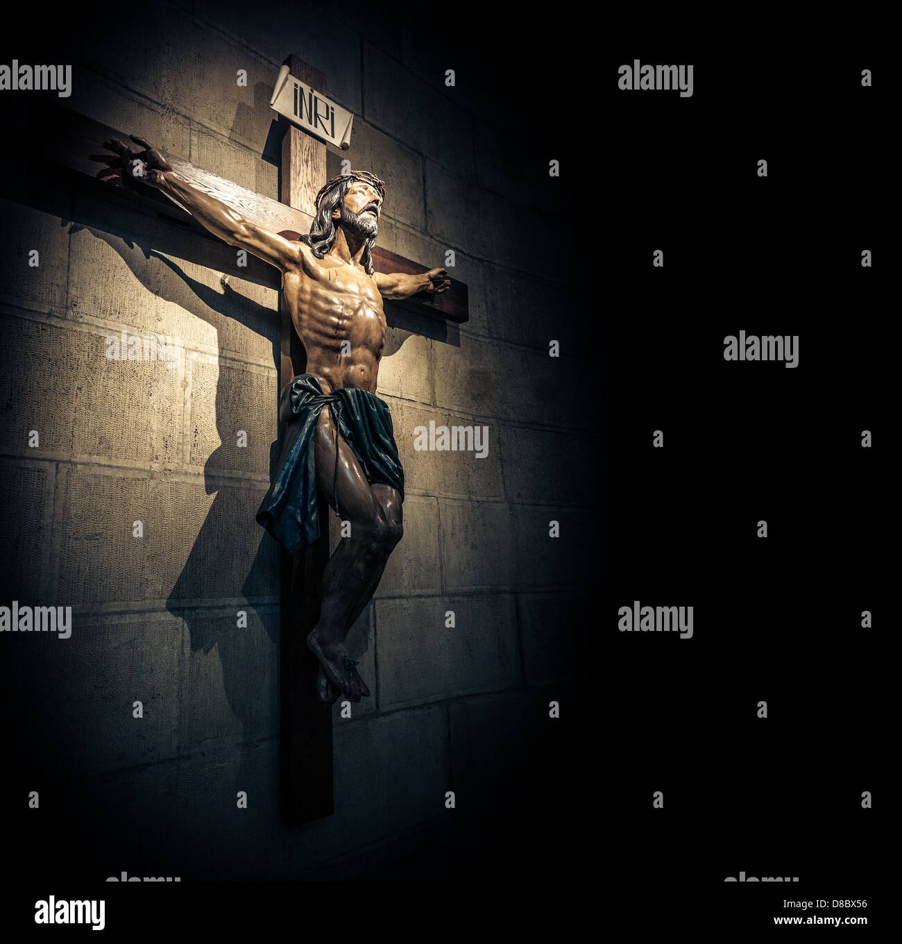Kruzifix an der Wand im Rampenlicht in alten dunklen Kirche oder Kathedrale. Jesus Christus am Kreuz. Religion, glaube und Hoffnung. Stockfoto