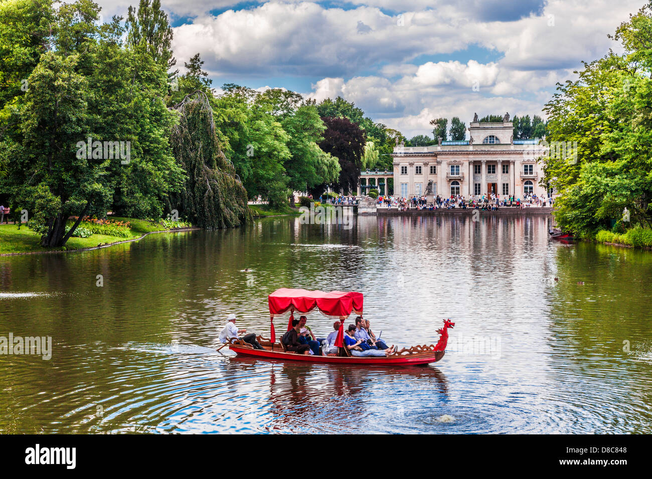 Touristen genießen eine Gondelfahrt auf dem See im Łazienki Park Łazienkowski, größte in Warschau mit dem Palast im Hintergrund. Stockfoto