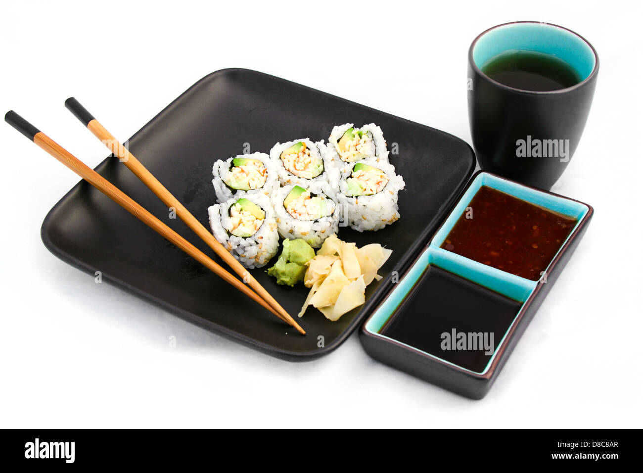 California Roll auf schwarze Platte mit Tee, Soja und Chili Saucen serviert. Stockfoto