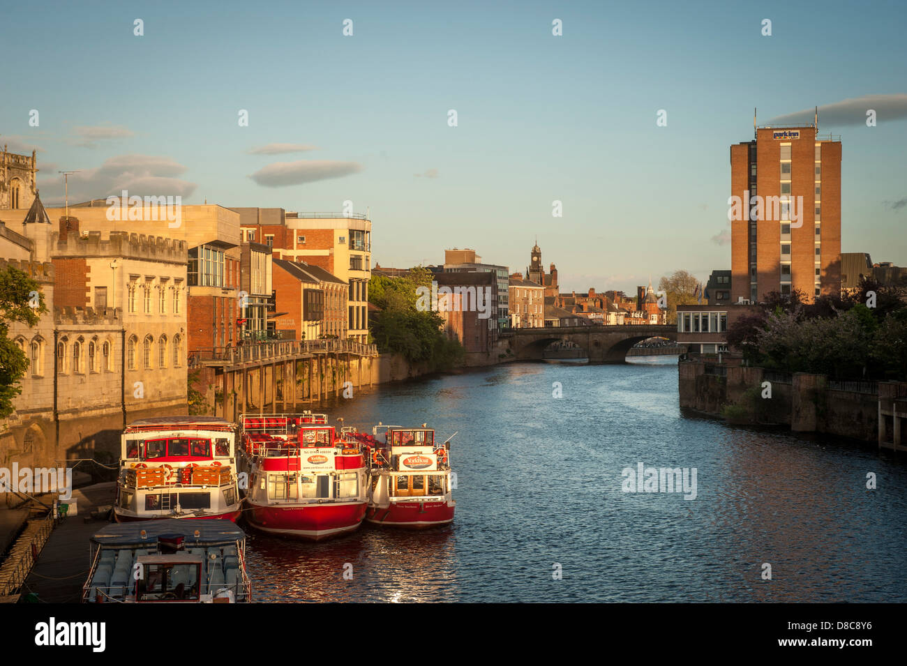 River Ouse an einem sonnigen Sommerabend mit festfahrenden Kreuzfahrtbooten und der Ouse Bridge in der Ferne, York, Großbritannien. Stockfoto