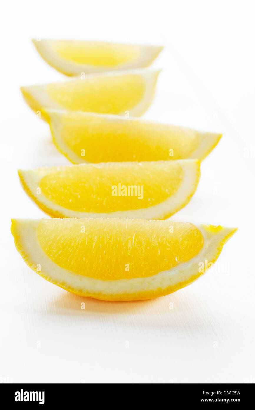 Zitronenspalten auf weißem Hintergrund - Zitronenspalten oder Scheiben auf einem weißen Hintergrund mit weichen Schatten. Stockfoto