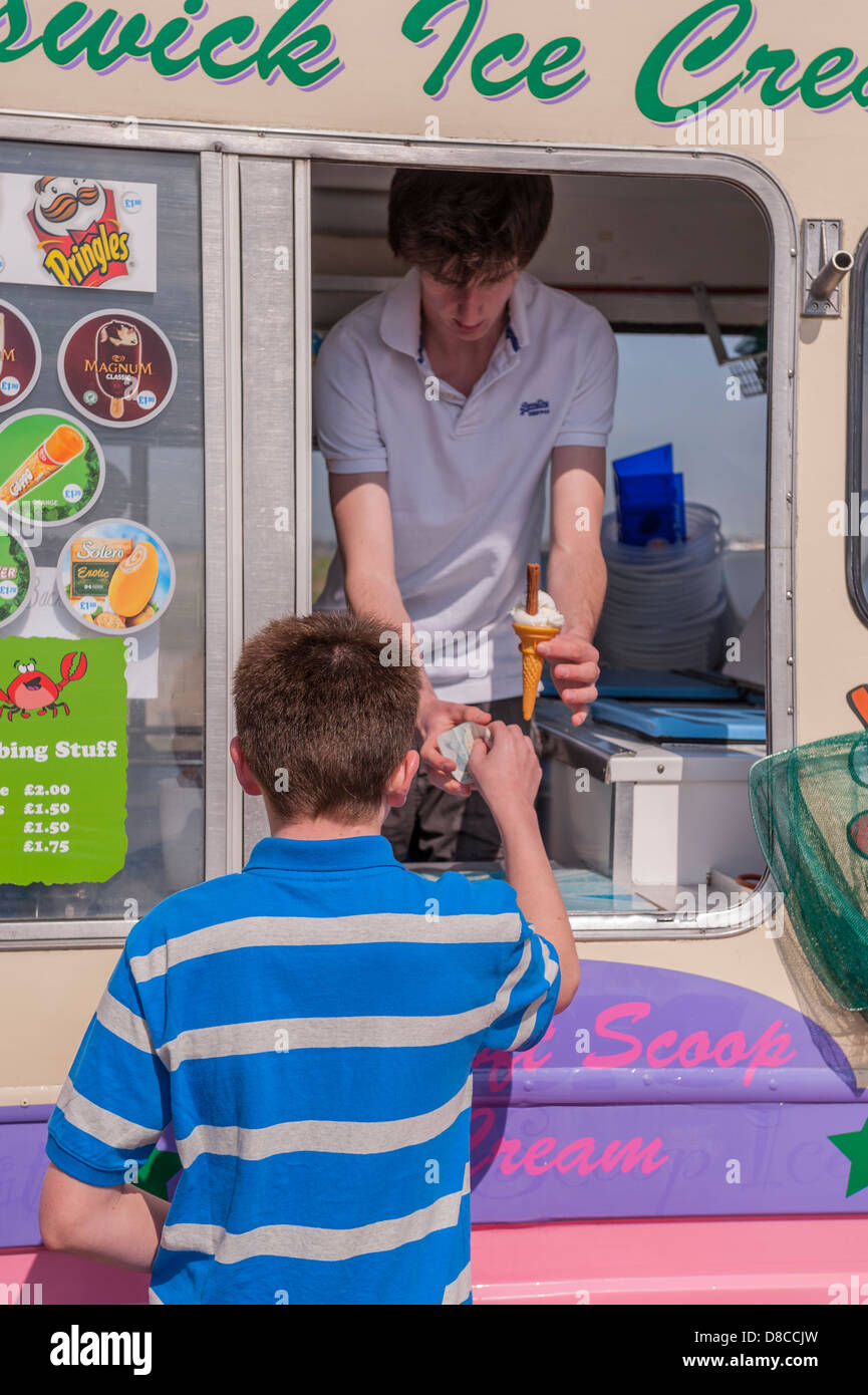 Ein 13 Einjahresjunge kauft ein Eis von einem van in Walberswick, Suffolk, England, Großbritannien, Uk Stockfoto