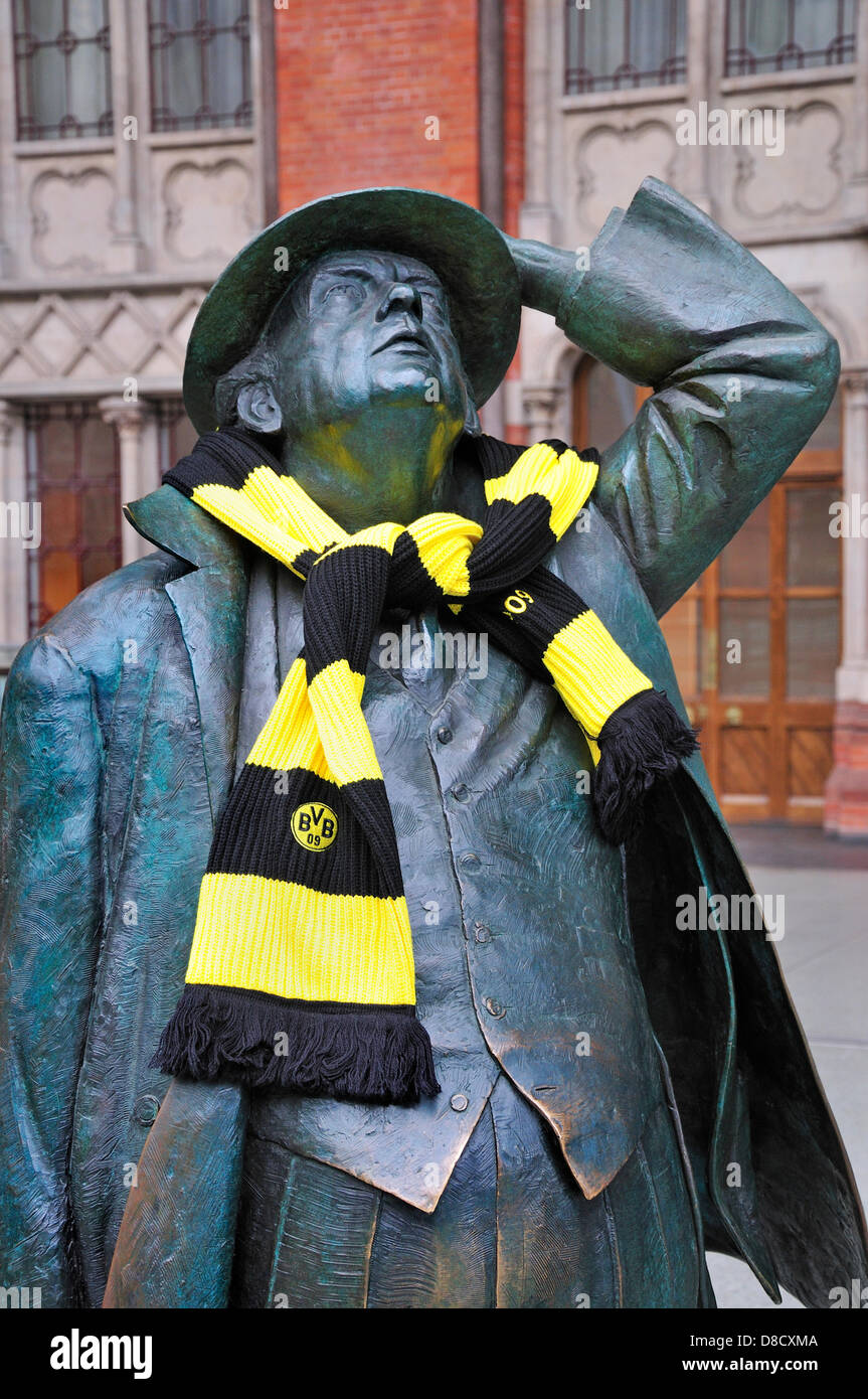 London, England, Großbritannien. Bahnhof St. Pancras. Statue: Sir John Betjeman (2007, Martin Jennings) im oberen Hallenfeld mit Borussia Dortmund Fußballschal (vor Champions League Finale 2013) Stockfoto