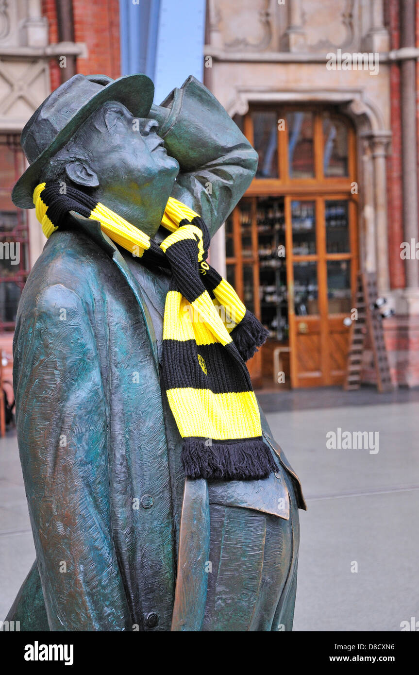 London, England, Großbritannien. Bahnhof St. Pancras. Statue: Sir John Betjeman (2007, Martin Jennings) im oberen Hallenfeld mit Borussia Dortmund Fußballschal (vor Champions League Finale 2013) Stockfoto