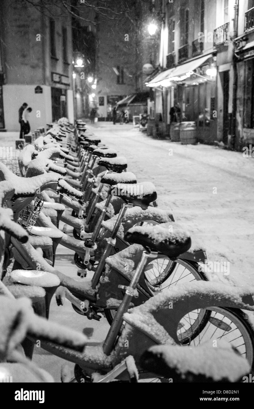 schneebedeckte Fahrräder in Paris Velib-Station. Stockfoto