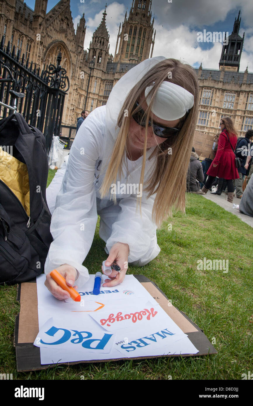 2013-05-25 Westminster, London.A Frau bereitet ihr Plakat tragen die Logos der mehrere bekannte Unternehmen, die sie beschuldigt, GVO-Praktiken an. Stockfoto